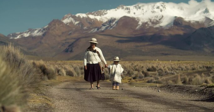 Bolivian grandmother and Son Walking with mountain range in the background