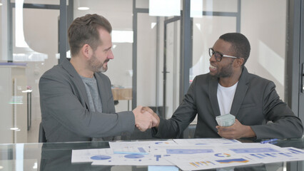 Young Man Giving Money to African Man and Shaking Hand