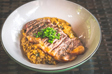 Risotto served with angus medium rare ribeye steak in a bowl