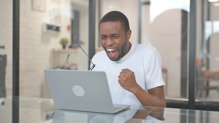 African American Man Celebrating Online Success on Laptop