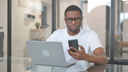African American Man Working with Smartphone and Laptop