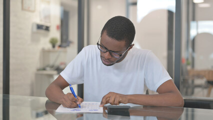 African American Man Doing Paperwork and Calculation