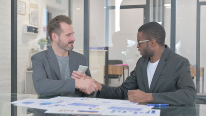 African Man Giving Money and Shaking Hand with Partner