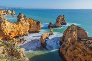 Long exposure image of the rocky Algarve coast with steep cliffs and seastacks in the vicinity of...