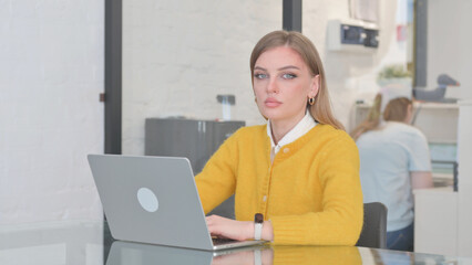 Blonde Casual Woman Looking at Camera while Using Laptop