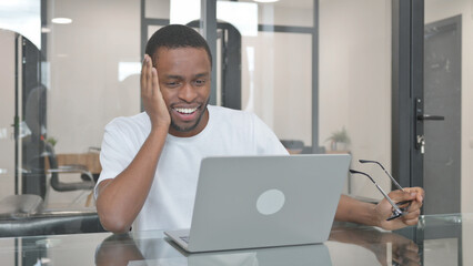 Excited Young African Man Celebrating Success on Laptop in Office