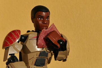 Fototapeta premium LEGO Star Wars figure of ex stormtrooper and force sensitive rebel Finn, eating a slice of salami in front of yellow wall. 