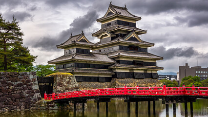 Red bridge in front of an ancient Japanese castle (Matsumoto, Nagano) - obrazy, fototapety, plakaty