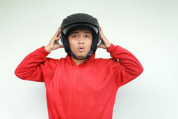Young Asian man shocked gesture while wear a motorcycle helmet. Safety concept.