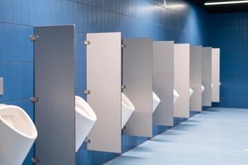 A row of urinals in a blue-tiled public toilet