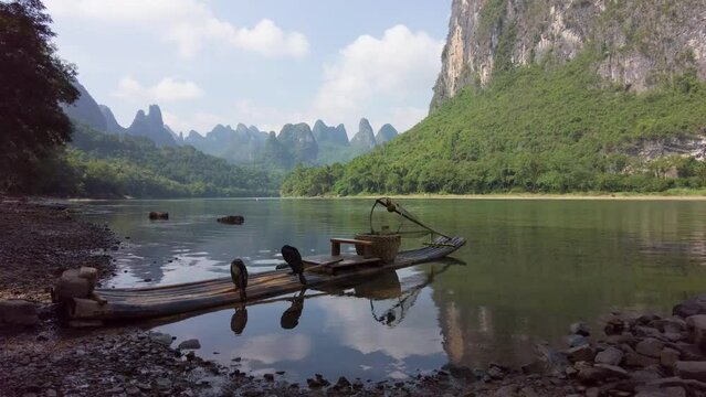 Landscape of karsten mountain along the Li River in Guilin with a bamboo raft and two comorants perching on it