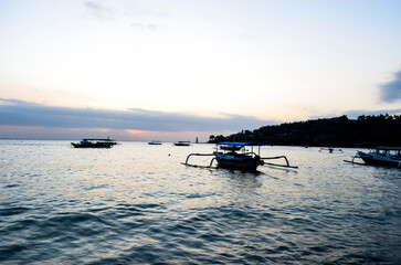 Obraz premium The view of the sunset with a very beautiful sky and boats leaning on Senggigi Beach