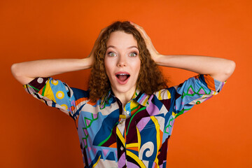 Photo of impressed cheerful cute girl wear trendy print clothes open mouth isolated on bright orange color background