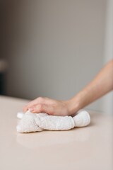 Clean Hands, Careful Hygiene: A Closeup of a Woman's White Hand Wiping a Table with a Towel in a Domestic Kitchen