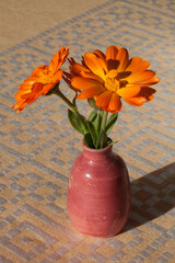 Fleurs de soucis dans un petit vase posé sur une nappe
