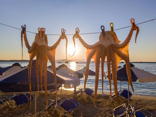 Octopuses hanging on a string to dry on a resort beach at dusk (Chania, Crete, Greece) - Powered by Adobe