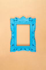 Empty blue painted baroque frame on beige color background, pop art style abstract backdrop