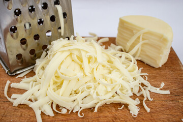 Romanian pressed cheese called cascaval, grated on a chopping board, soft focus close up