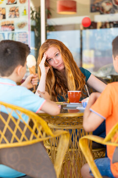 Stressed mother on a terrace of a coffee shop with her two children