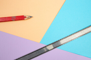 carpentry red crayon with a metal saw blade on colored background, abstract backdrop