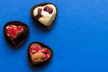 chocolate sweets in the form of a heart with fruits and nuts on a colored background. top view with space for text, holiday concept