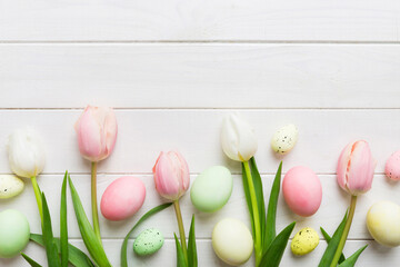 Happy Easter composition. Easter eggs on colored table with yellow Tulips. Natural dyed colorful...