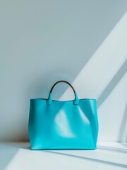 Light blue leather female handbag on white table under sunlight.