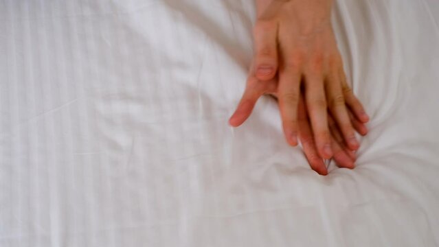 Man and woman holding hands lying in bed making love, hands close-up. Sex, intimate life, pleasure and love concept. Two lovers having a sex holding hands, sensual gesture.