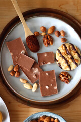 Cup of tea or coffee, cookies, macaroons, chocolate, various nuts and cocoa powder on wooden table. Top view.
