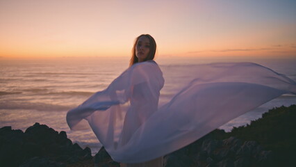 Sensual girl waving cloth performing contemporary dance in summer sunset hill