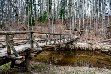 Wooden bridge over the river leading to the Vilce Nature Park. Latvia. Wooden path in early spring.