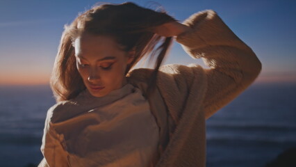 Relaxed girl dancing alone in sunset ocean side closeup. Woman looking camera