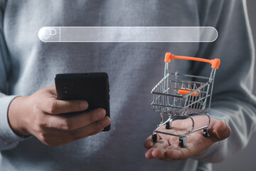 Shopping cart with search bar and man holding mobile phone. Businessman or entrepreneur working...