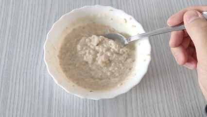 A man stirs oatmeal in a plate. Cooling the porridge. Proper nutrition.