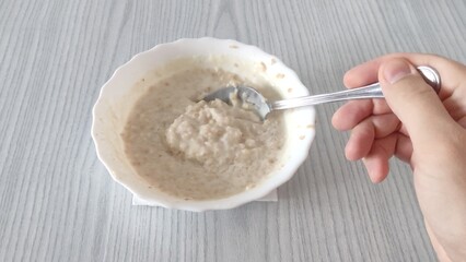 A man stirs oatmeal in a plate. Cooling the porridge. Proper nutrition.