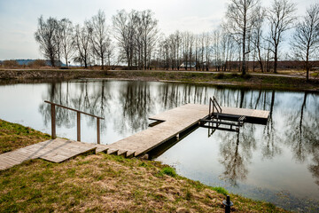 Pier on the pond. Wooden bridge in spring time with blue lake.