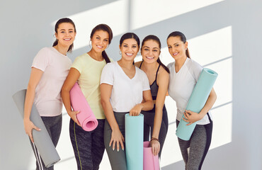 Yoga enthusiasts with mats. Portrait of smiling group of young beautiful women posing after...