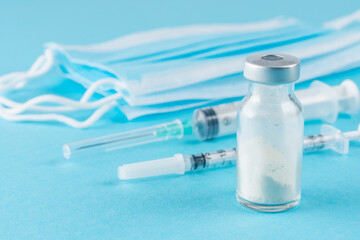Vaccine vial glass with a syringe on blue background.