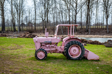 Pink agricultural tractor in a rural area. Rural landscape in early spring.
