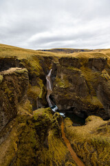 A stunning waterfall cascades down the bedrock in the middle of a picturesque Fjadrargljufur...