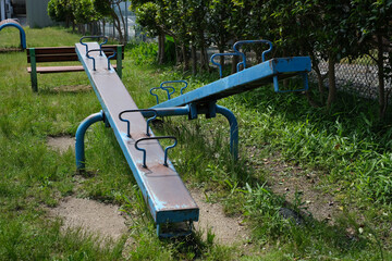 公園の青いシーソーと木製ベンチ