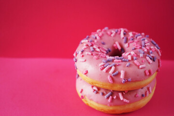 Donuts in pink glaze with sprinkles on a pink background