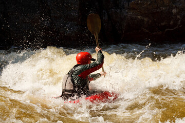 Man in red helmet paddling on water in a boat for outdoor recreation