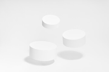 Abstract scene - three round white tilt podiums for cosmetic products mockup, fly in hard light, shadow on white background. For presentation skin care products, gifts, advertising in minimal style.