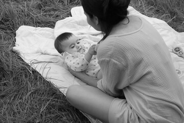 Mother's loving gaze meets her baby's laughter in the green grass. An embodiment of pure, uninterrupted quality time.