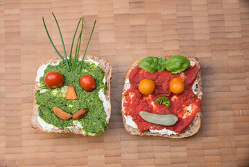 two wholemeal sandwiches with funny faces on a wooden tray