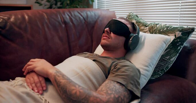 Psilocybin therapy, sofa and man with headphones and eye mask for depression, anxiety and wellness. Mental health, psychology and person with sensory deprivation for treatment, counseling and help