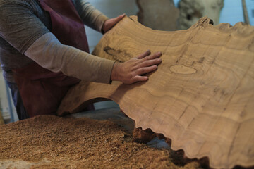 The woodworker examines the grain patterns of a beautiful burl slab. Each line and knot narrates...