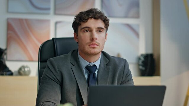 Serious ceo sitting desk with laptop in luxury office closeup. Thoughtful man