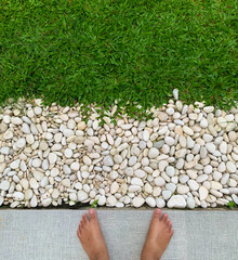 Feet on Fresh Green Grass with White Pebbles, Bare feet on grass, concept of relaxation and connection with nature